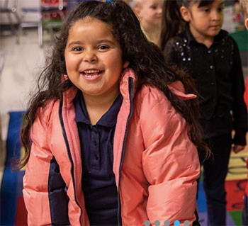 A smiling child with a pink jacket on