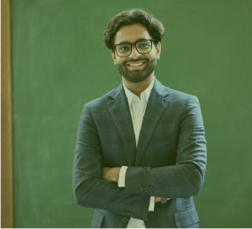 Man in a blazer in front of a chalk board