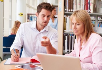 Two professionals having a discussion at a laptop in a library